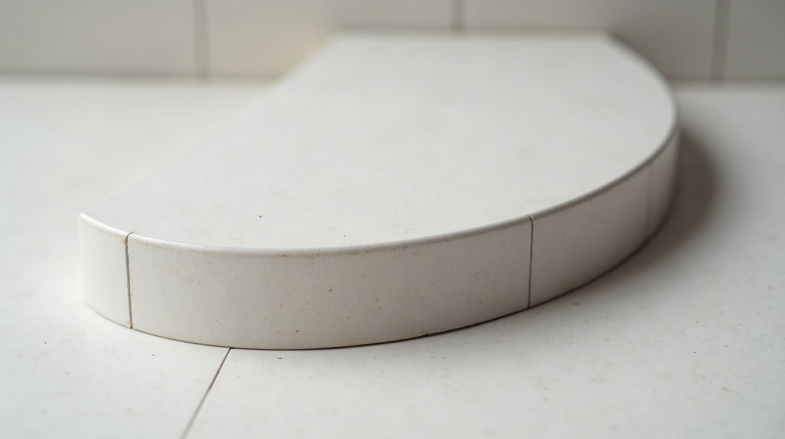 Coupe d'un échantillon de béton ciré posé sur une chape, montrant les couches successives du système appliqué