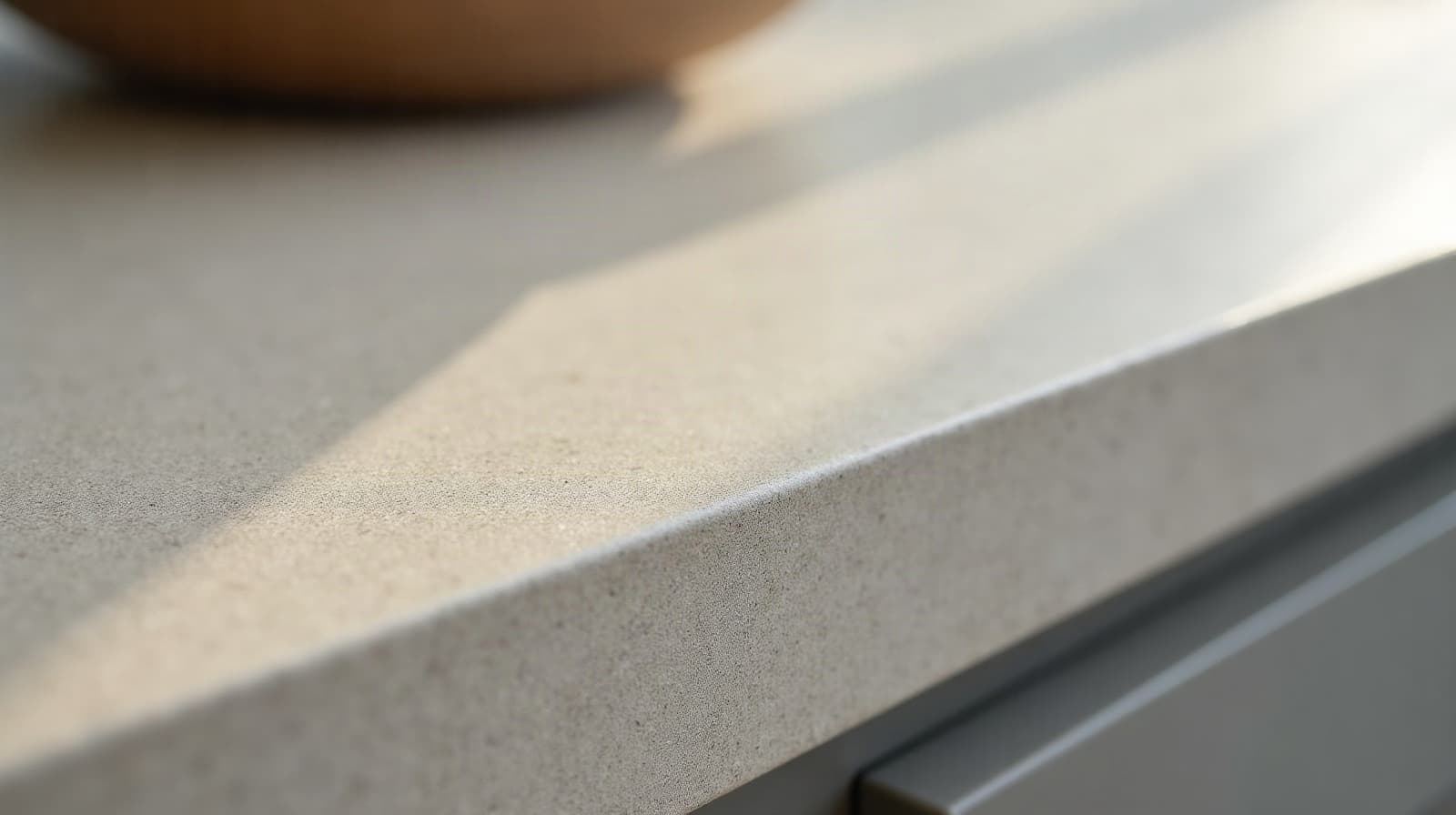 Angle d'un plan de travail de cuisine en béton ciré fini, jonction nette avec une crédence assortie en arrière-plan flou